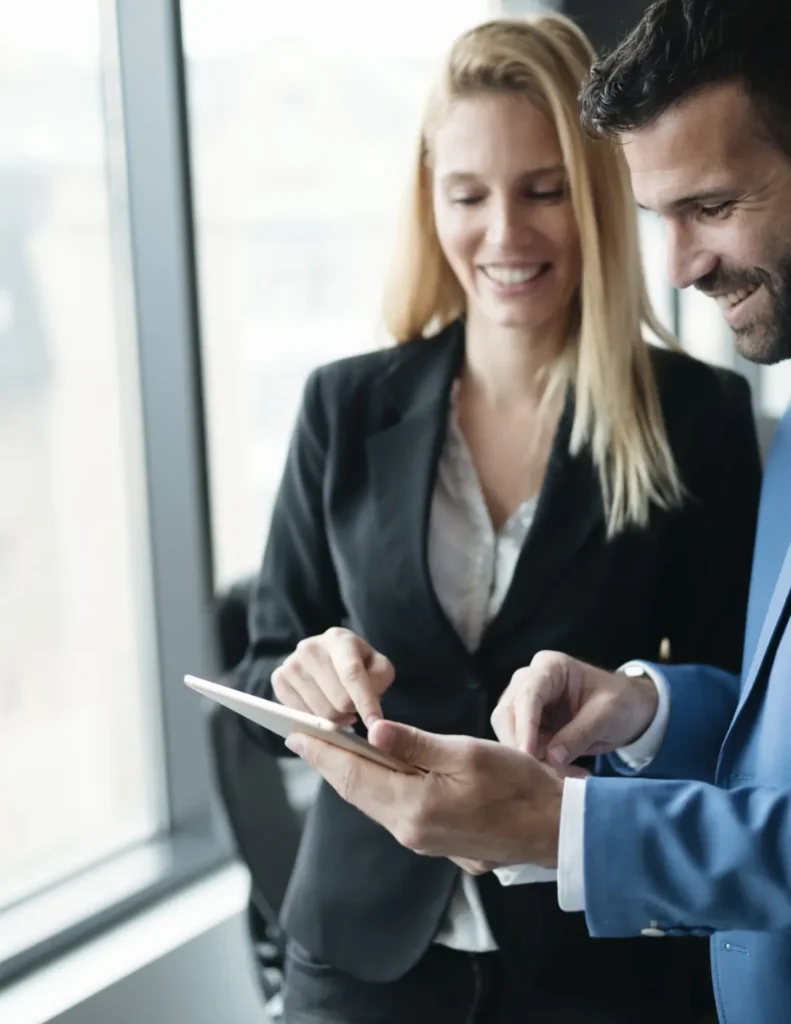 Deux collaborateurs consultant une tablette près d’une fenêtre