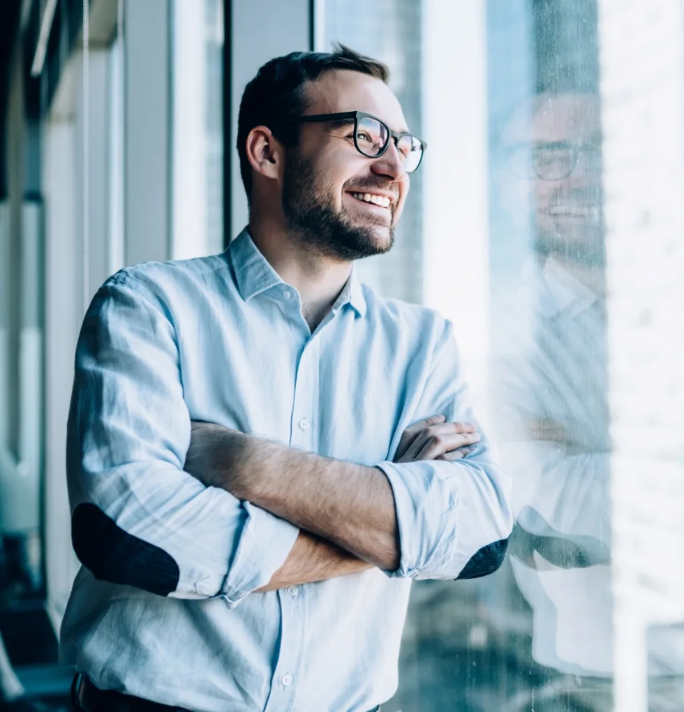 Dirigeant souriant regardant vers l’horizon, les bras croisés